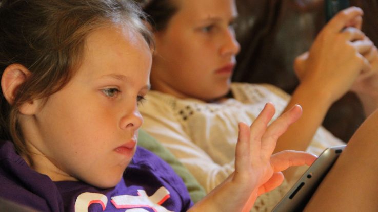 Chapel Herron, front, and her sister Lillie enjoy some screen time at their home in Orlando, Florida.